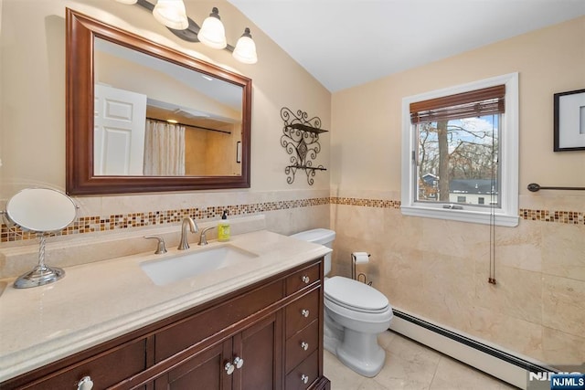 bathroom with a wainscoted wall, tile walls, toilet, baseboard heating, and vanity