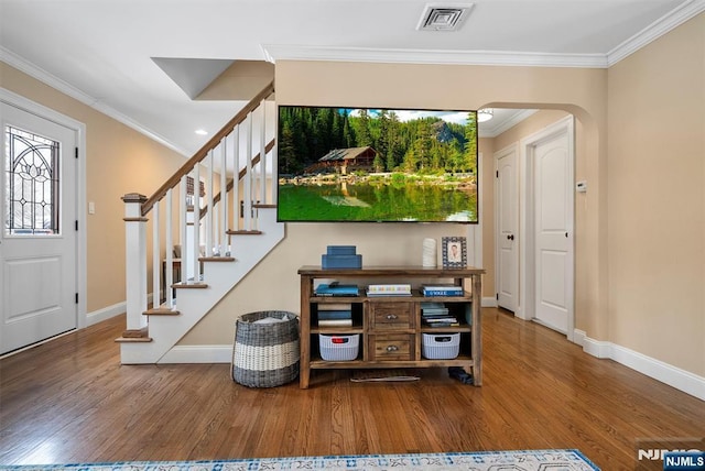 entryway with visible vents, arched walkways, wood finished floors, stairs, and crown molding