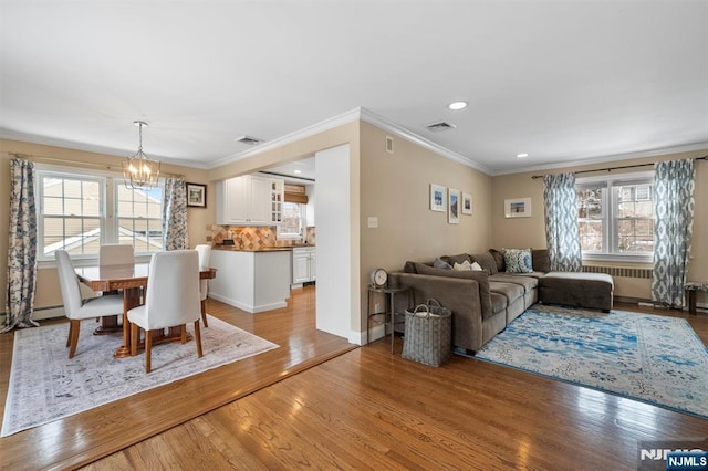 dining space featuring an inviting chandelier, crown molding, visible vents, and wood finished floors