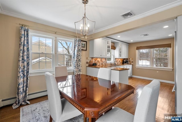 dining space with light wood-type flooring, baseboards, visible vents, and crown molding