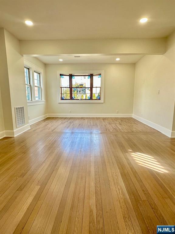 unfurnished room featuring hardwood / wood-style flooring, baseboards, and visible vents