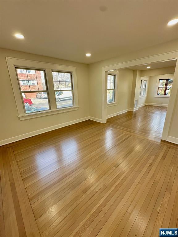 empty room with light wood-style flooring, baseboards, and recessed lighting