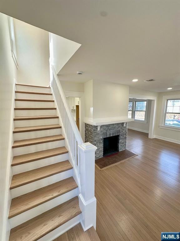 stairway featuring a fireplace, recessed lighting, visible vents, wood finished floors, and baseboards