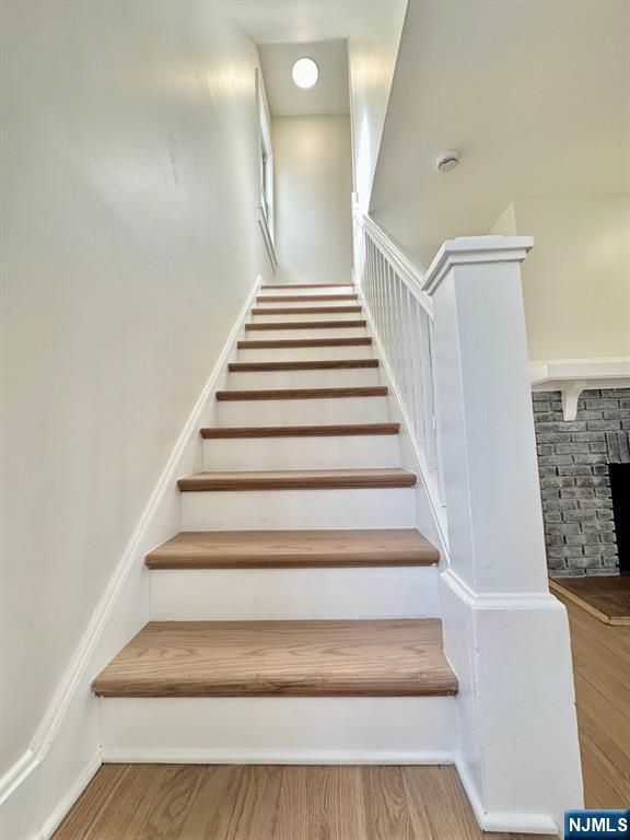 stairway featuring a fireplace, baseboards, and wood finished floors