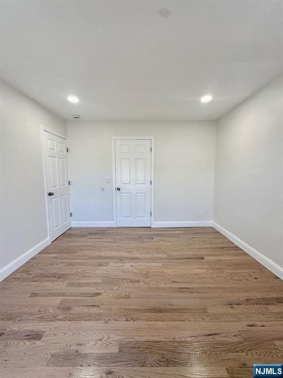 empty room featuring light wood finished floors, baseboards, and recessed lighting