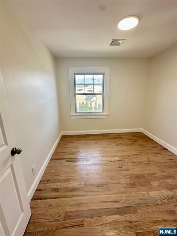 empty room featuring visible vents, baseboards, and wood finished floors