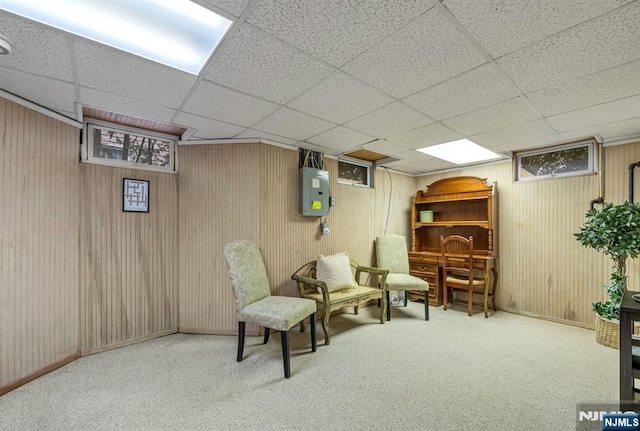 sitting room featuring a drop ceiling, carpet flooring, electric panel, and baseboards