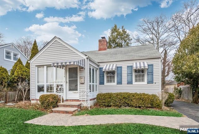 bungalow-style home with fence and a chimney