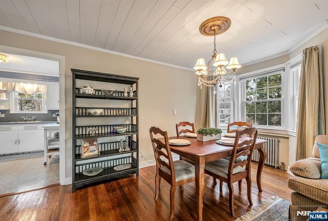 dining room featuring ornamental molding, radiator, an inviting chandelier, and hardwood / wood-style flooring