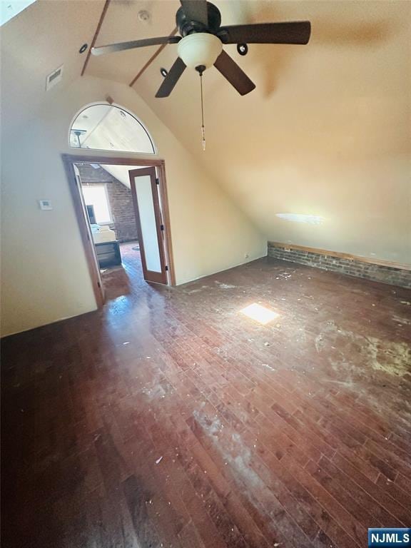 additional living space featuring dark wood-style floors, visible vents, and high vaulted ceiling