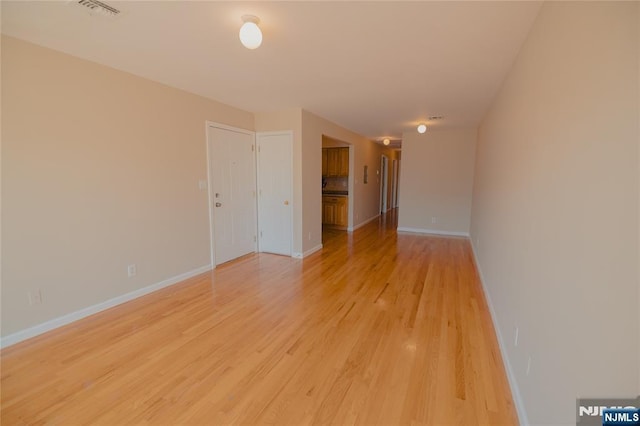 unfurnished room featuring light wood-style flooring, visible vents, and baseboards