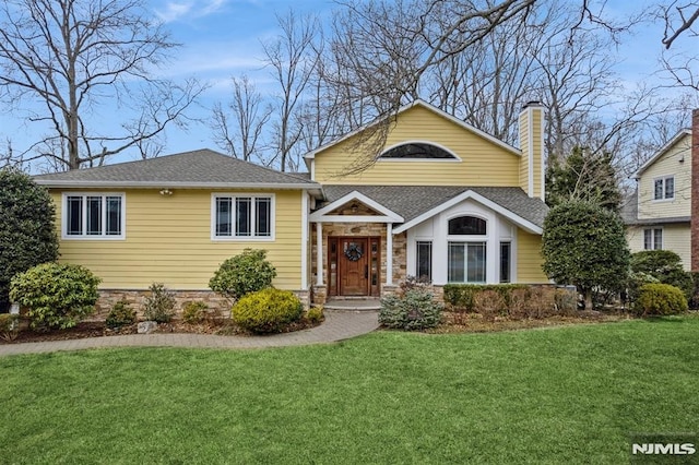 view of front of house with a front lawn, a chimney, and a shingled roof