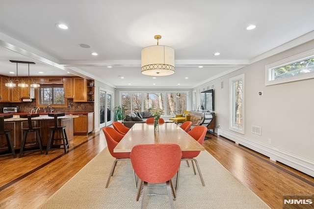 dining space featuring light wood-style floors, baseboards, beamed ceiling, and recessed lighting