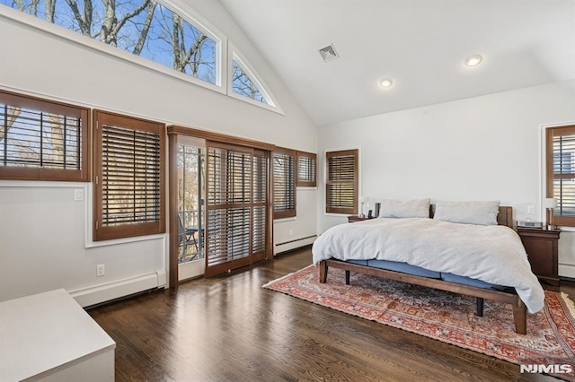 bedroom featuring a baseboard heating unit, dark wood-style floors, visible vents, and high vaulted ceiling