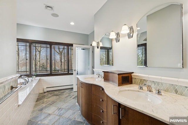 bathroom featuring double vanity, baseboard heating, a sink, and visible vents