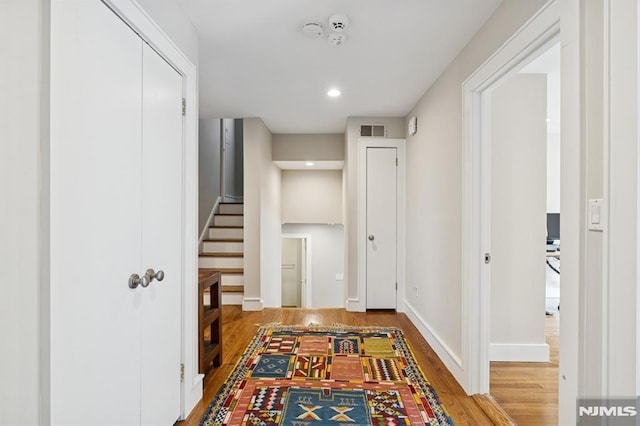 hallway featuring recessed lighting, visible vents, wood finished floors, baseboards, and stairs