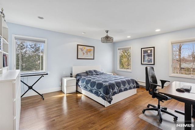 bedroom with baseboards, baseboard heating, wood finished floors, and recessed lighting