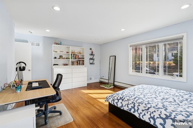 bedroom with baseboard heating, wood finished floors, and recessed lighting