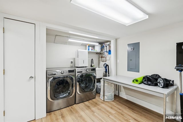 clothes washing area featuring laundry area, light wood-style flooring, electric panel, and separate washer and dryer