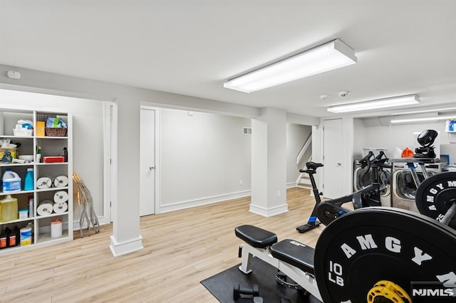 exercise room with baseboards, visible vents, and light wood finished floors