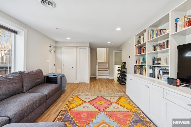 living area featuring light wood-type flooring, stairs, visible vents, and recessed lighting