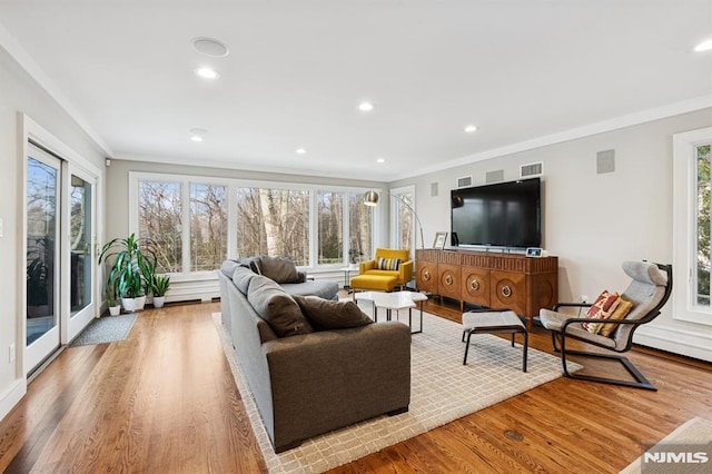 living area with recessed lighting, light wood-type flooring, visible vents, and crown molding