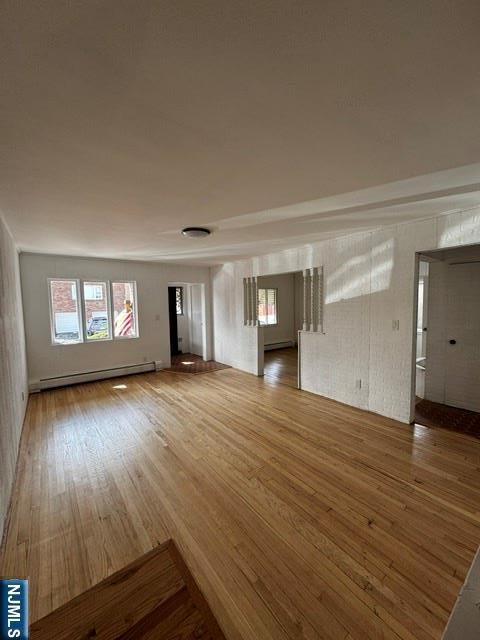 unfurnished living room featuring baseboard heating and wood finished floors