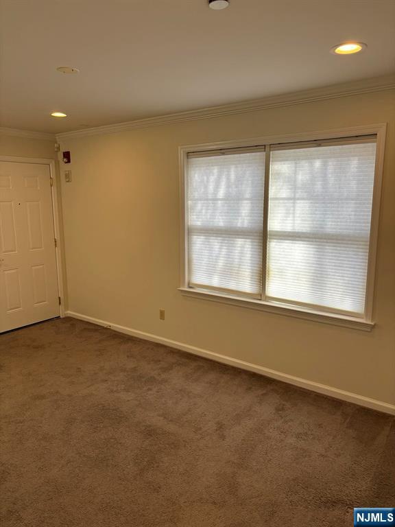 spare room with ornamental molding, recessed lighting, dark carpet, and baseboards