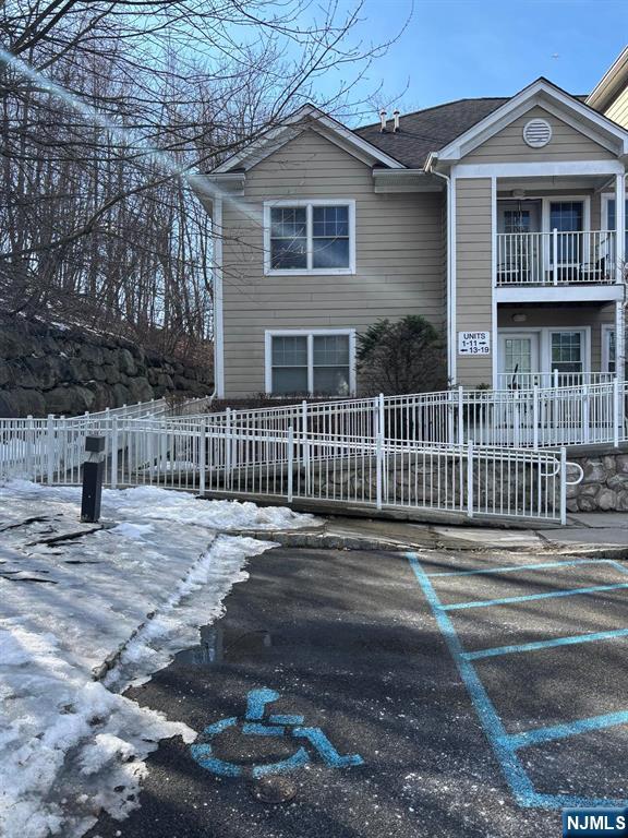 view of front of home featuring uncovered parking, a fenced front yard, and a balcony