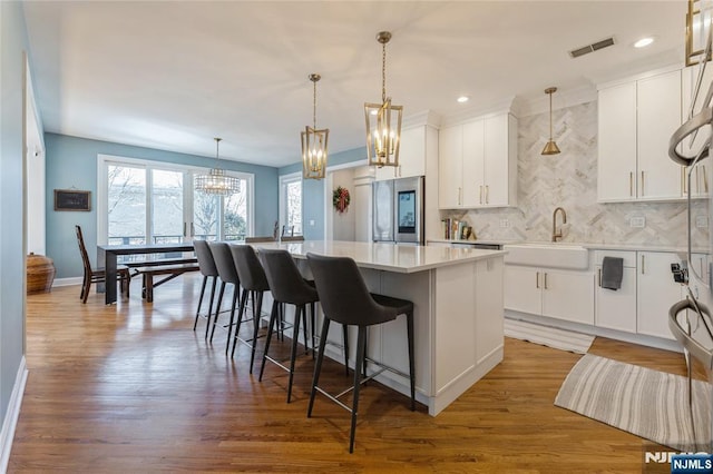 kitchen featuring a sink, visible vents, a center island, smart refrigerator, and an inviting chandelier