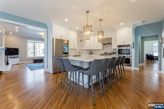 kitchen featuring appliances with stainless steel finishes, backsplash, white cabinetry, and under cabinet range hood