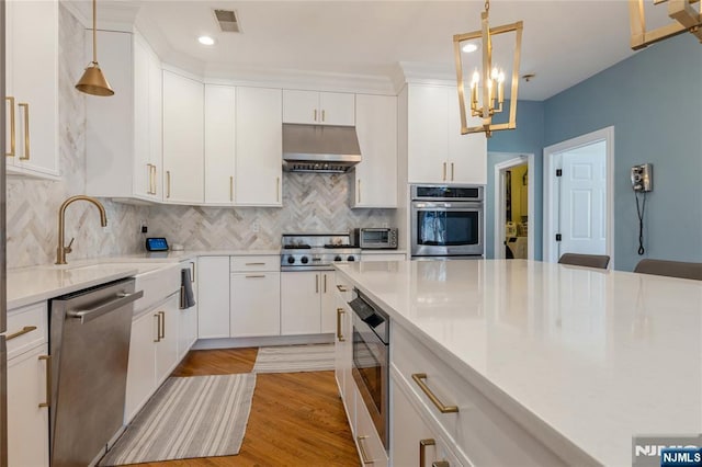 kitchen with visible vents, appliances with stainless steel finishes, light countertops, under cabinet range hood, and a sink