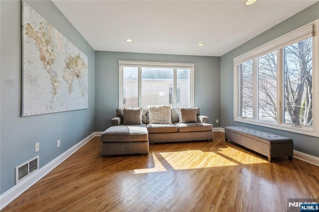 living area with baseboards, visible vents, wood finished floors, and recessed lighting