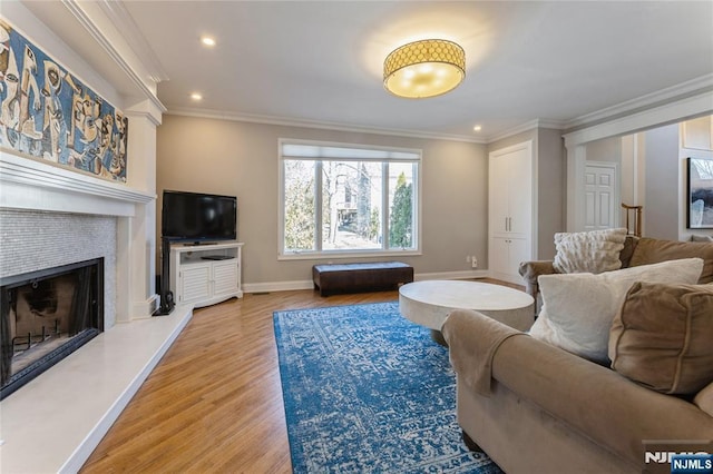 living area with a fireplace, recessed lighting, ornamental molding, wood finished floors, and baseboards