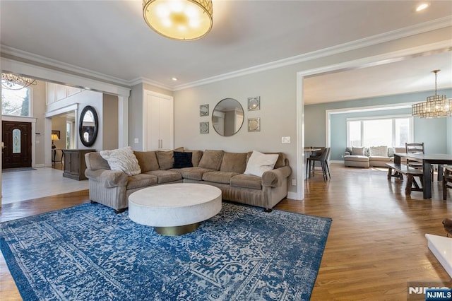 living room with baseboards, ornamental molding, a notable chandelier, and wood finished floors