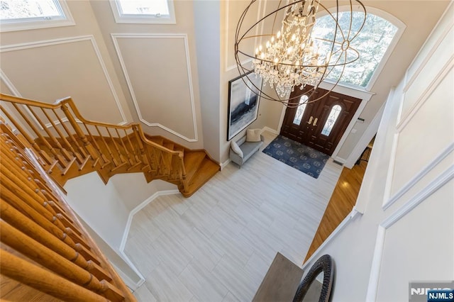 entrance foyer with a chandelier, stairway, a high ceiling, and light wood finished floors