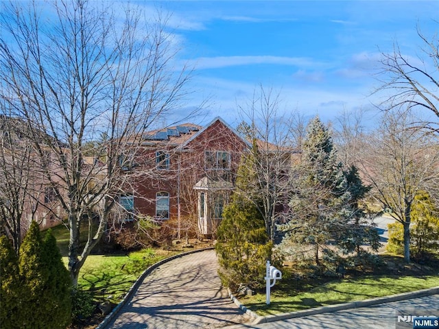 view of front of house featuring solar panels, a front lawn, and driveway