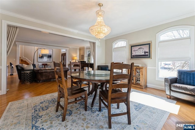 dining room featuring light wood finished floors, baseboards, a chandelier, and ornamental molding