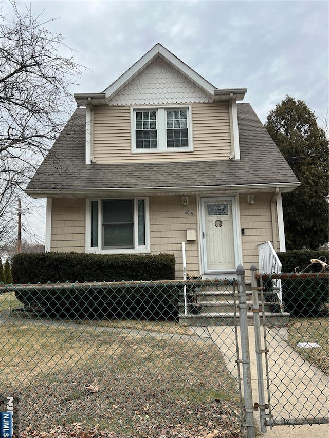 view of front of property with a fenced front yard, a gate, and roof with shingles