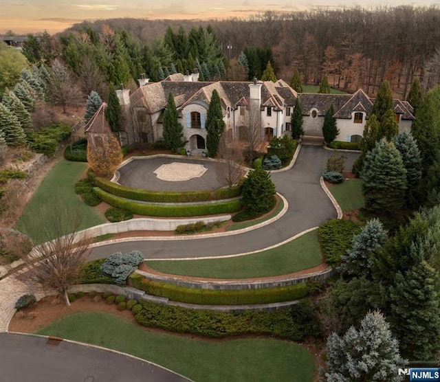 aerial view at dusk featuring a wooded view