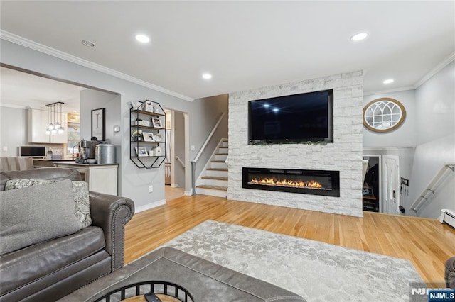 living area with recessed lighting, stairway, ornamental molding, a stone fireplace, and wood finished floors