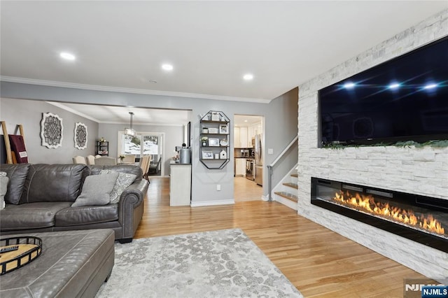 living area with crown molding, a fireplace, and wood finished floors