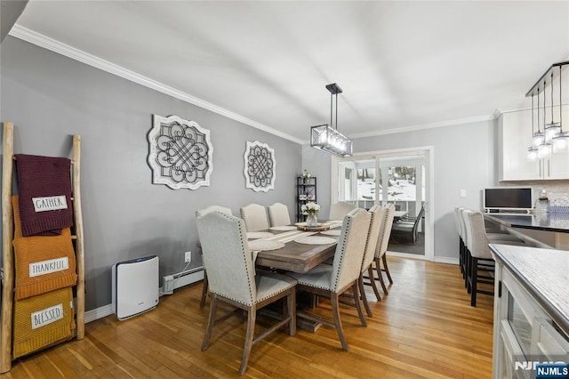 dining space featuring light wood finished floors, ornamental molding, and baseboard heating