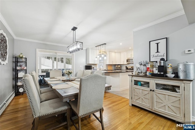 dining space featuring ornamental molding, a baseboard radiator, and light wood-style flooring