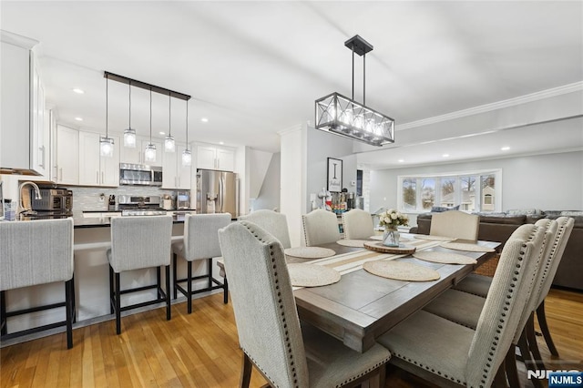 dining area with crown molding, light wood-style flooring, and recessed lighting