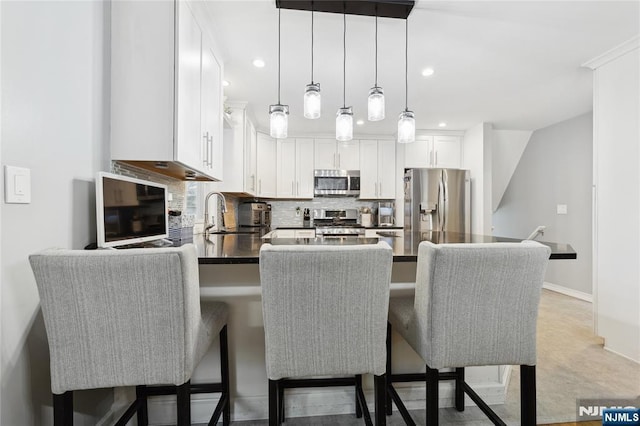 kitchen with appliances with stainless steel finishes, dark countertops, a breakfast bar, and white cabinets