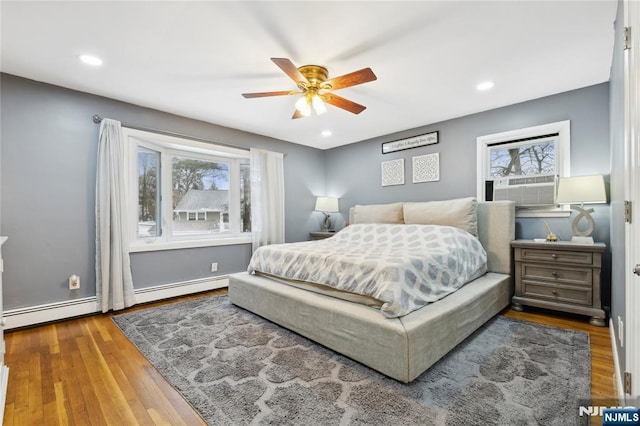 bedroom featuring recessed lighting, a baseboard radiator, wood finished floors, and cooling unit