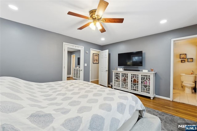 bedroom featuring baseboards, ensuite bath, ceiling fan, wood finished floors, and recessed lighting