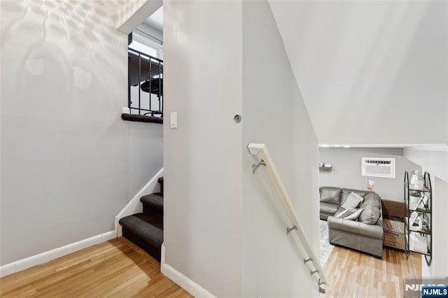 stairway featuring baseboards, wood finished floors, and a wall mounted AC