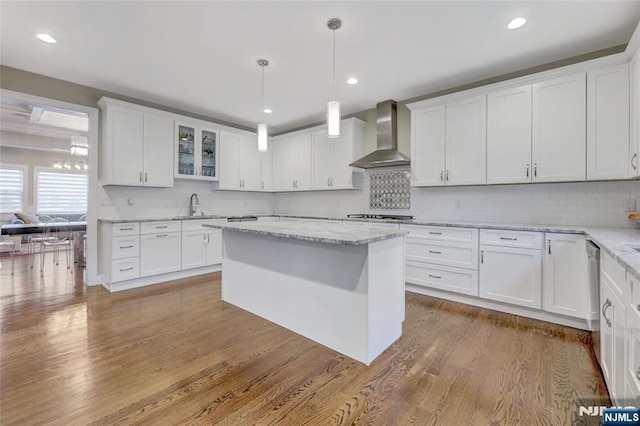 kitchen with white cabinets, wall chimney exhaust hood, and wood finished floors